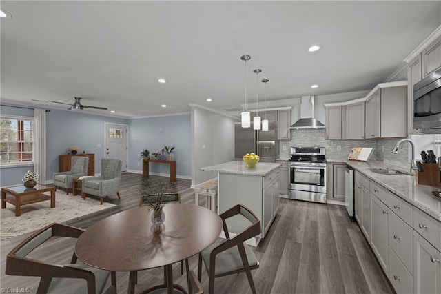 kitchen featuring gray cabinetry, a center island, hanging light fixtures, wall chimney exhaust hood, and stainless steel appliances