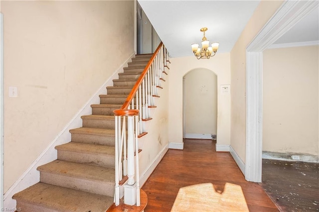 stairway with a chandelier, hardwood / wood-style flooring, and crown molding