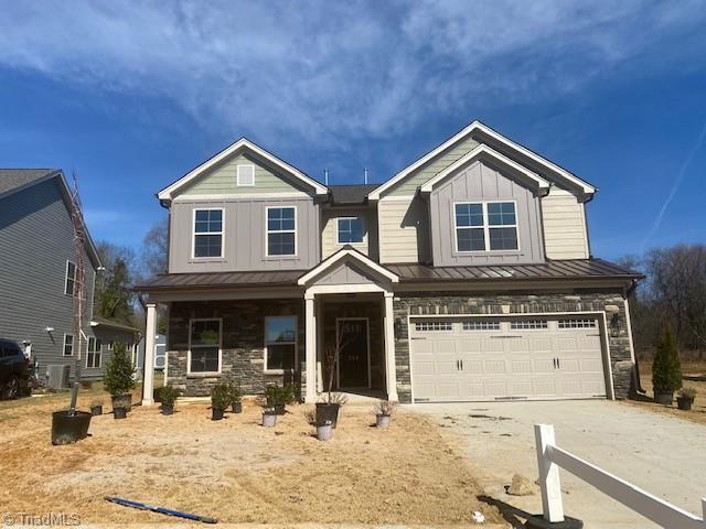 craftsman inspired home featuring concrete driveway, stone siding, an attached garage, a standing seam roof, and board and batten siding