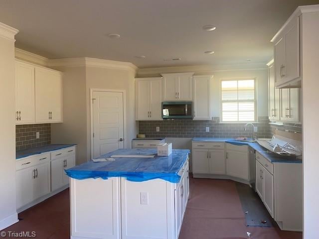 kitchen with dark countertops, a sink, a center island, and white cabinets