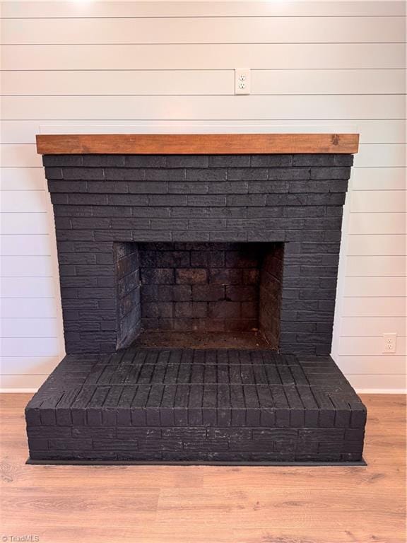 room details featuring wooden walls, a fireplace, baseboards, and wood finished floors