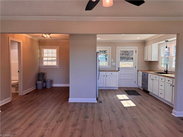 kitchen featuring stainless steel appliances, light countertops, white cabinets, a sink, and wood finished floors