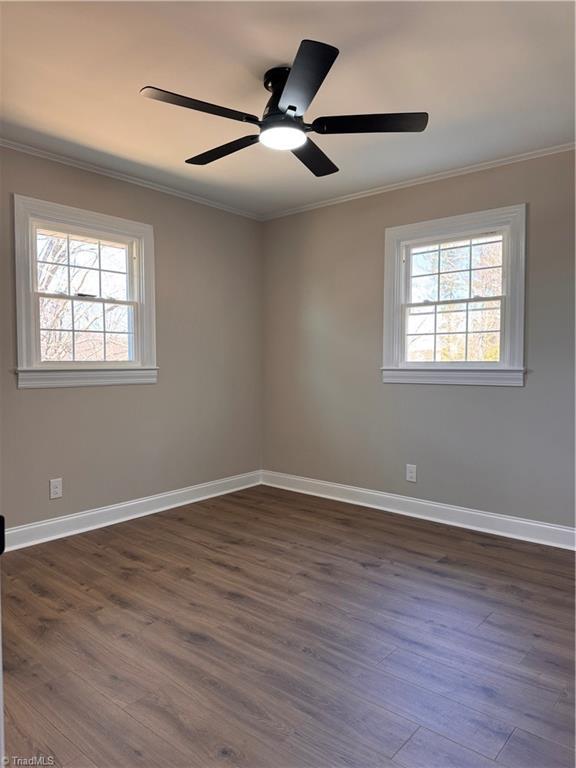 unfurnished room featuring ornamental molding, dark wood-style flooring, baseboards, and a ceiling fan