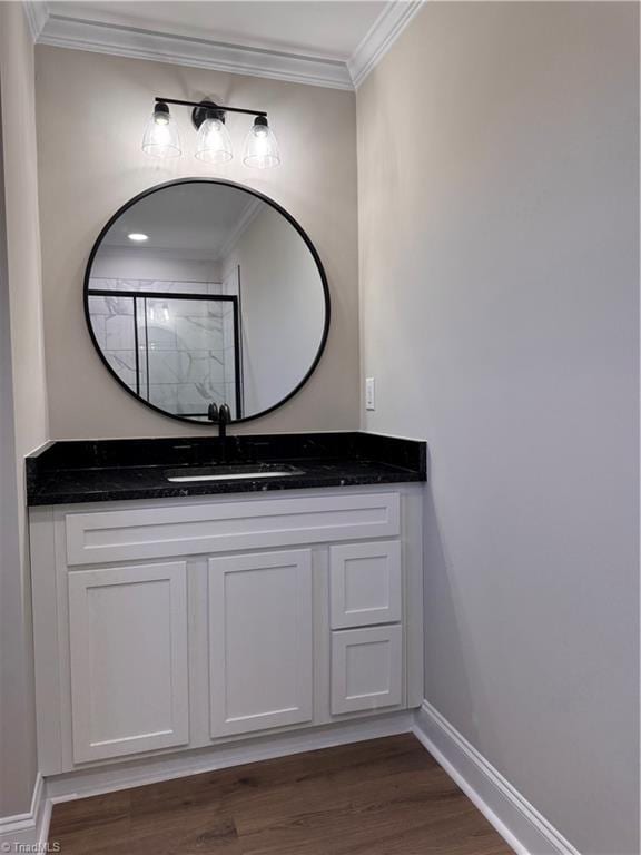 full bathroom with wood finished floors, vanity, baseboards, ornamental molding, and walk in shower