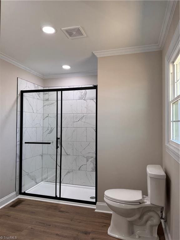 full bath featuring ornamental molding, visible vents, a shower stall, and wood finished floors