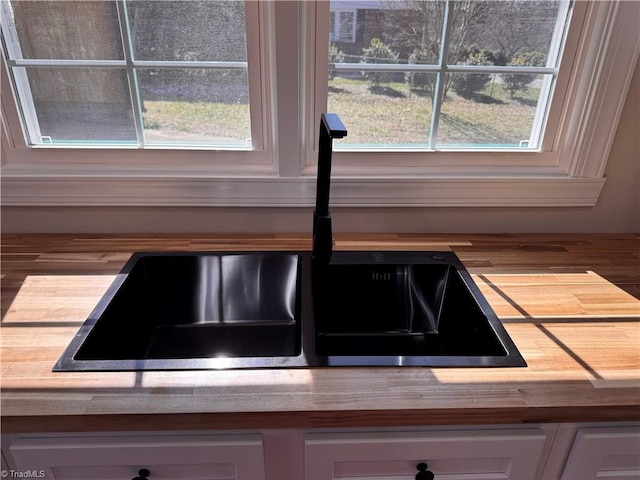 interior details with a sink and white cabinetry