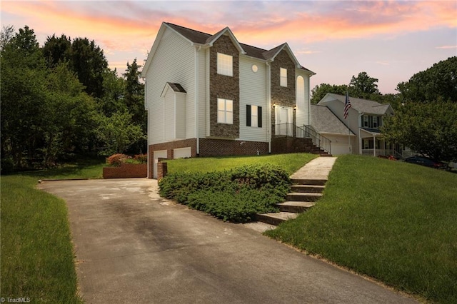 view of front facade featuring a garage, a front yard, stone siding, and concrete driveway
