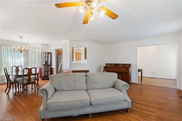 living area featuring crown molding, wood finished floors, and ceiling fan with notable chandelier