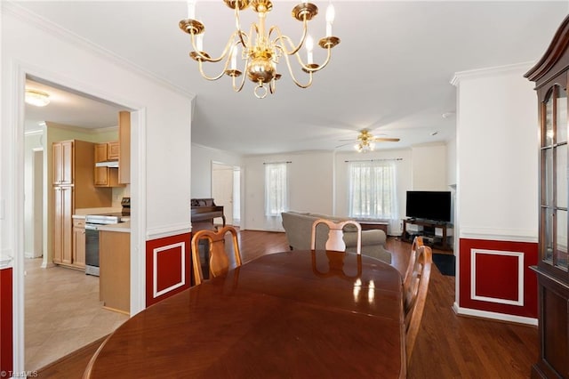 dining area with ceiling fan with notable chandelier, ornamental molding, and wainscoting