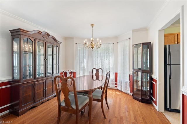 dining area with ornamental molding, light wood finished floors, and a chandelier