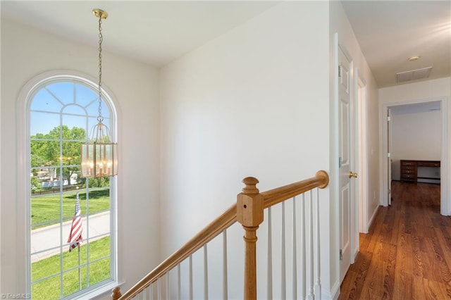 hallway with wood finished floors, a chandelier, an upstairs landing, and a healthy amount of sunlight