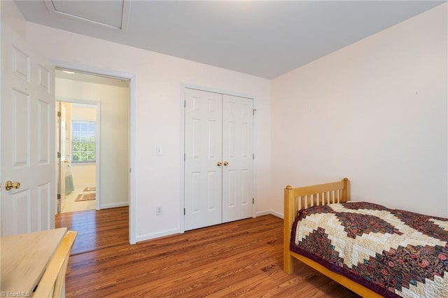 bedroom with baseboards, wood finished floors, and a closet