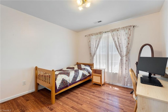bedroom with baseboards, wood finished floors, and visible vents