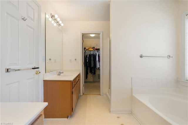 bathroom with vanity, a bath, and a spacious closet