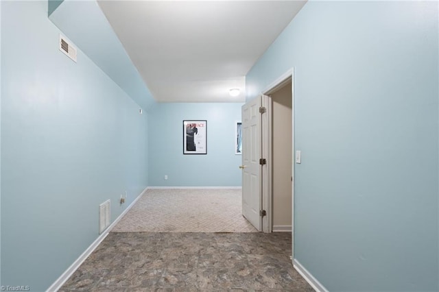 hall with visible vents, baseboards, and stone finish floor