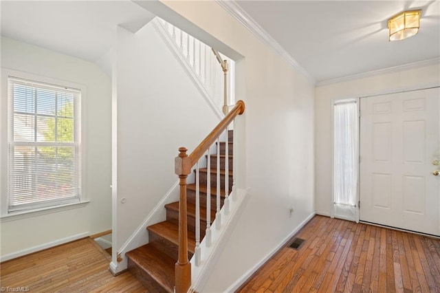 foyer with visible vents, stairs, crown molding, and hardwood / wood-style flooring