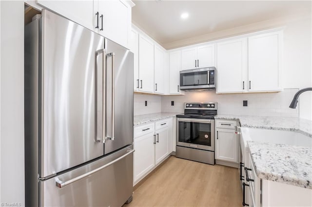 kitchen with light wood finished floors, decorative backsplash, white cabinets, and stainless steel appliances