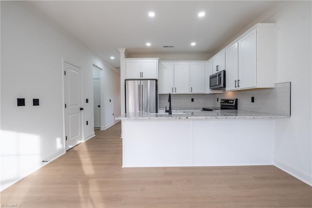 kitchen with visible vents, light wood finished floors, a peninsula, appliances with stainless steel finishes, and white cabinetry