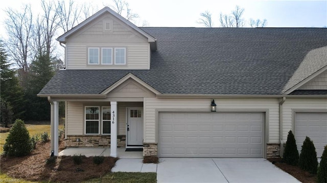 craftsman-style house featuring stone siding, driveway, a porch, and an attached garage