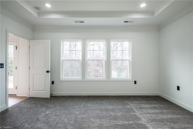 empty room featuring a tray ceiling, visible vents, and carpet floors