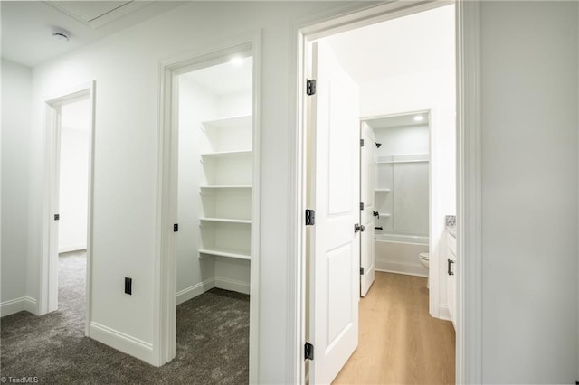 hall featuring baseboards and light colored carpet