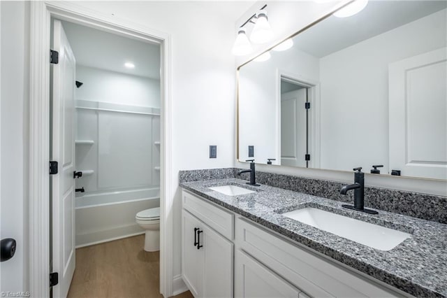 full bathroom featuring a sink, toilet, wood finished floors, and double vanity