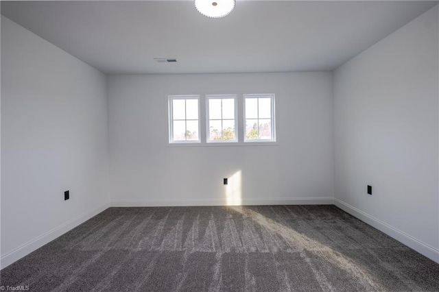 empty room with baseboards, visible vents, and dark carpet