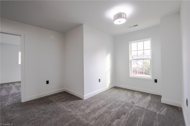 carpeted empty room featuring visible vents and baseboards