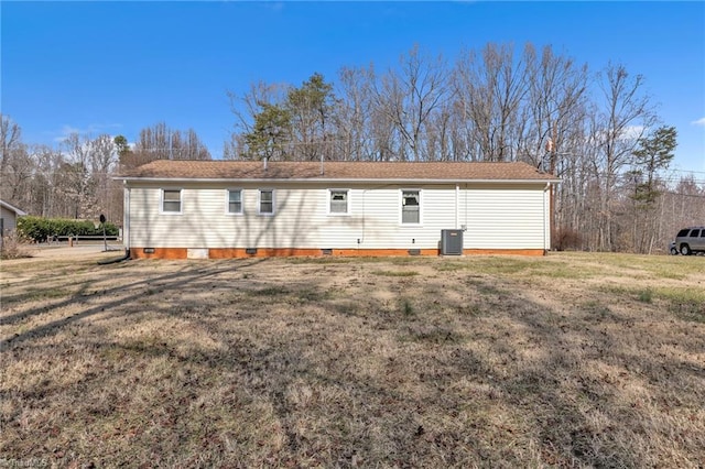 back of property with central AC and a lawn