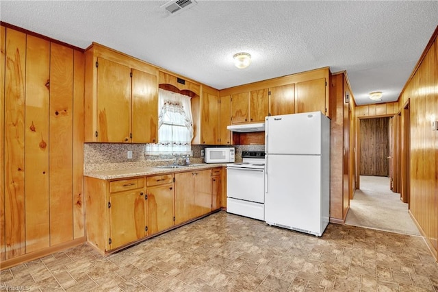 kitchen featuring sink, backsplash, white appliances, and wood walls