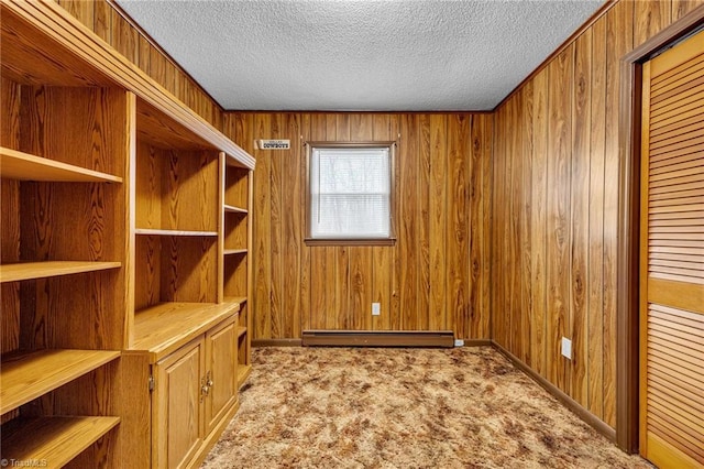 unfurnished office with wooden walls, a baseboard heating unit, light colored carpet, and a textured ceiling