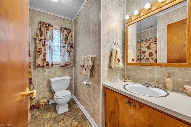 bathroom featuring tile walls, vanity, ornamental molding, toilet, and a textured ceiling