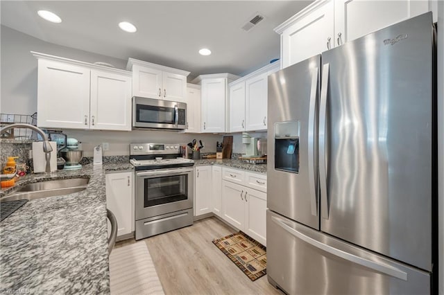 106 Oak Ridge Dr, Archdale, NC 27263 - kitchen featuring appliances with stainless steel finishes, a sink, white cabinetry, light stone countertops, and light wood-style flooring