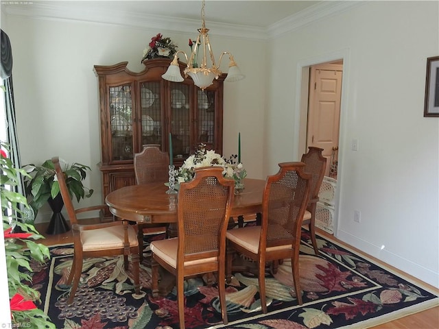 dining room with crown molding, hardwood / wood-style flooring, and an inviting chandelier