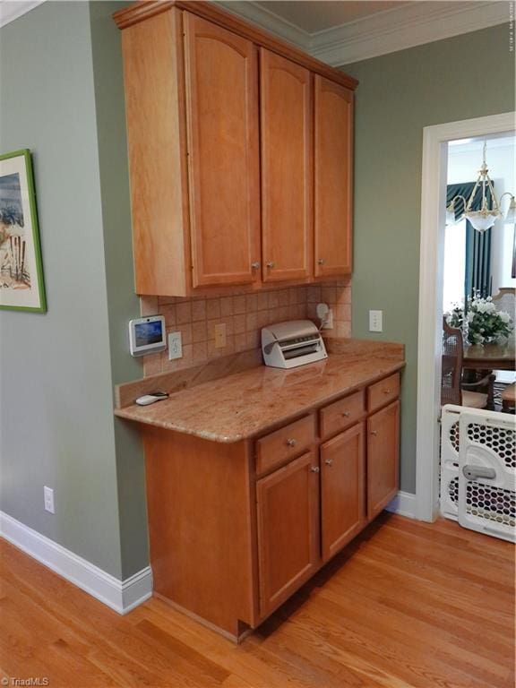 kitchen with a notable chandelier, light wood-type flooring, crown molding, and tasteful backsplash