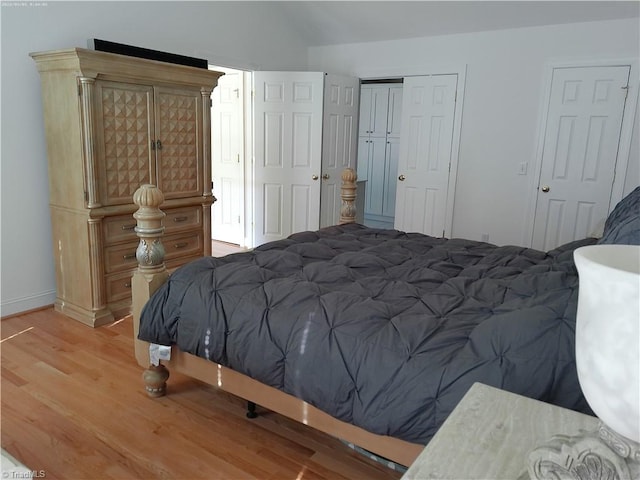 bedroom with light wood-type flooring and vaulted ceiling