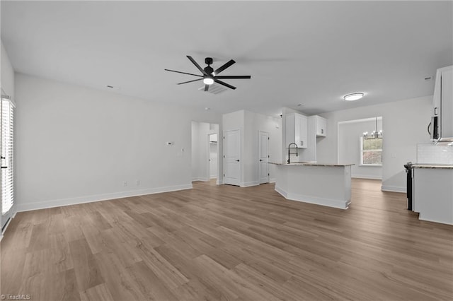 1329 Union Cross Rd, Kernersville, NC 27284 - unfurnished living room featuring a sink, a chandelier, light wood-style flooring, ceiling fan, and baseboards