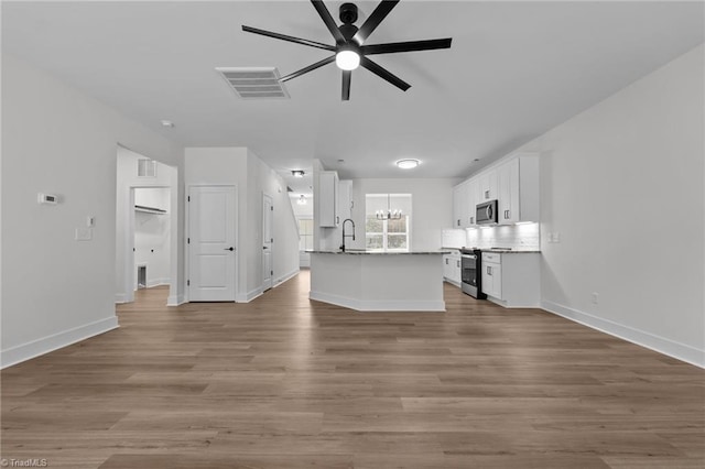 1329 Union Cross Rd, Kernersville, NC 27284 - unfurnished living room with a ceiling fan, a chandelier, wood finished floors, and baseboards