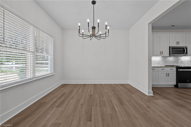 1329 Union Cross Rd, Kernersville, NC 27284 - unfurnished dining area with a chandelier, wood finished floors, and baseboards