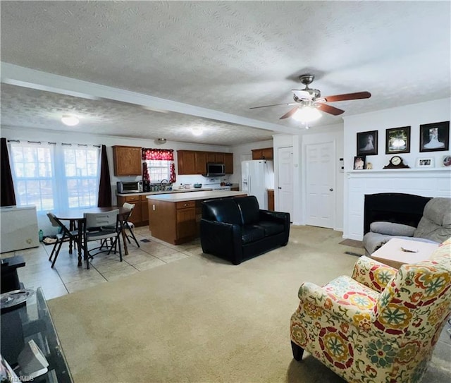 living room with ceiling fan, light colored carpet, and a textured ceiling