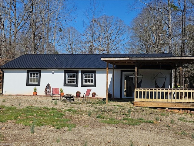 back of property featuring metal roof, an outdoor fire pit, and stucco siding