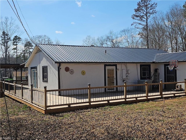 back of house featuring metal roof and a wooden deck