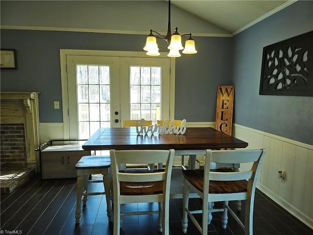 dining space with dark wood-type flooring, vaulted ceiling, french doors, and wainscoting