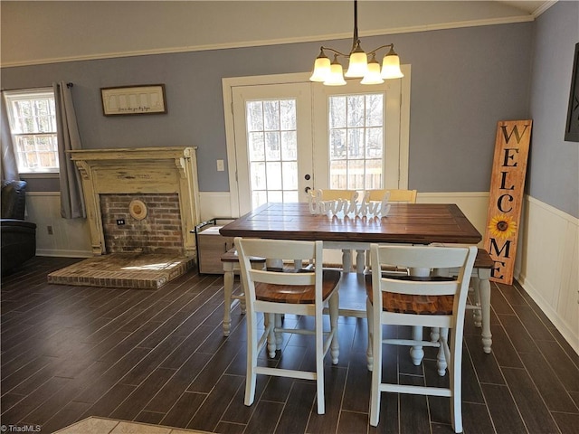 dining area featuring ornamental molding, wood finish floors, wainscoting, and a notable chandelier