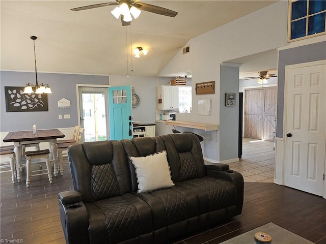 living room with a wealth of natural light, visible vents, vaulted ceiling, and wood finished floors