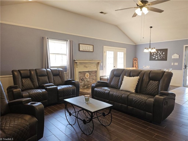 living area featuring lofted ceiling, ceiling fan with notable chandelier, wood finished floors, and visible vents