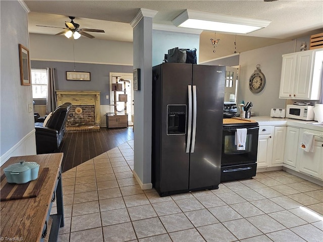 kitchen with light tile patterned flooring, fridge with ice dispenser, black / electric stove, and white microwave