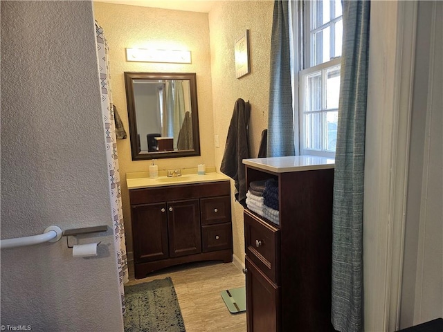 bathroom featuring a textured wall, wood finished floors, and vanity