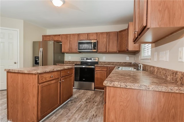 kitchen featuring a kitchen island, light wood-type flooring, sink, and appliances with stainless steel finishes