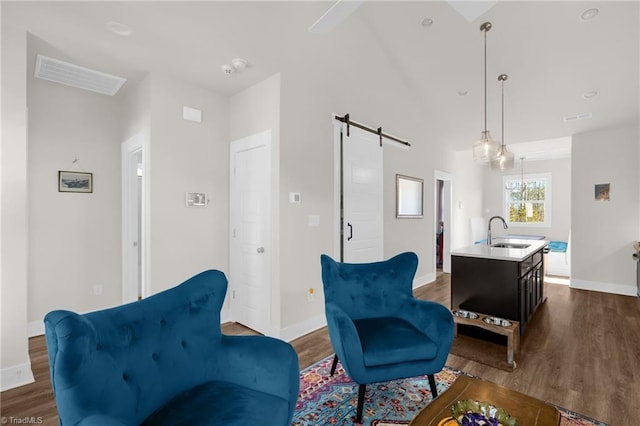 living area with dark wood-style floors, a barn door, visible vents, and baseboards